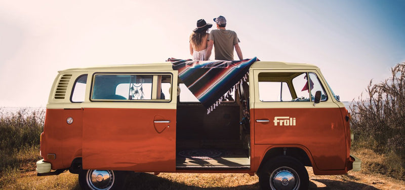 couple sitting on roof of vw camper van