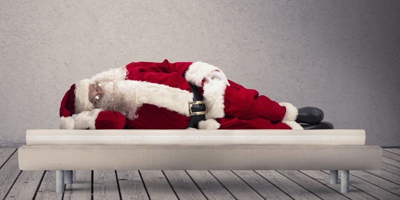 Santa Claus shown sleeping on bed